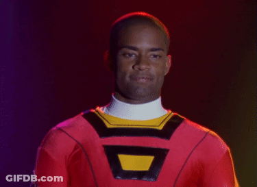 Man In Red Costume With Yellow Triangle Smiling GIF