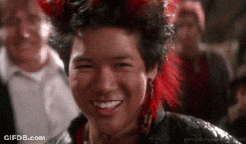 Man In Red Feathered Headdress Smiling In Crowd GIF