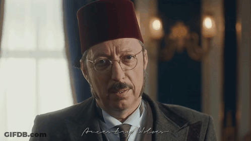 Man In Red Hat And Glasses Looking At Camera GIF