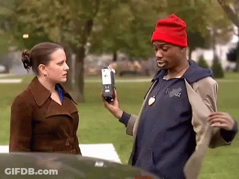 Man In Red Hat Holding Cell Phone In Front Of Woman In Brown Coat GIF