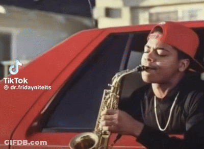 Man In Red Hat Playing Saxophone In Front Of Car GIF