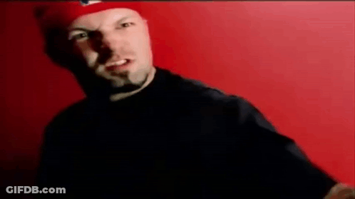 Man In Red Hat Standing Before Red Wall GIF