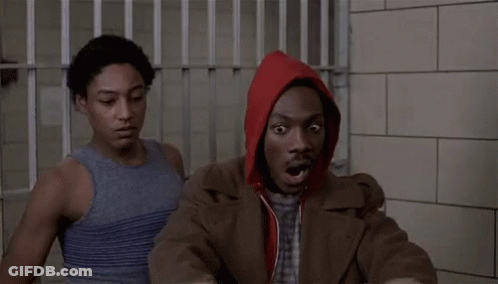 Man In Red Hoodie Sitting In Jail Cell With Another Man GIF