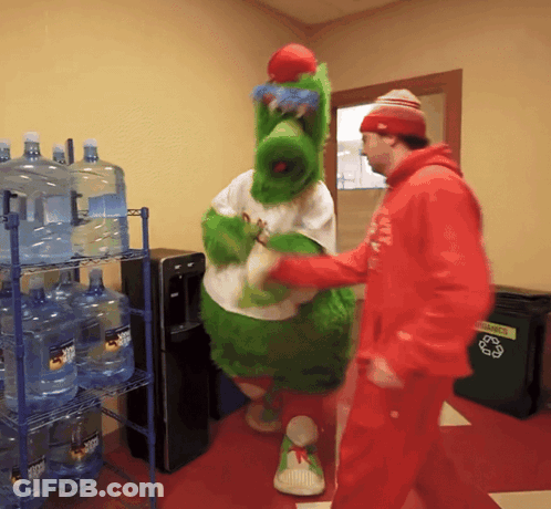 Man In Red Hoodie Talks To Green Mascot At Recycling Bin GIF