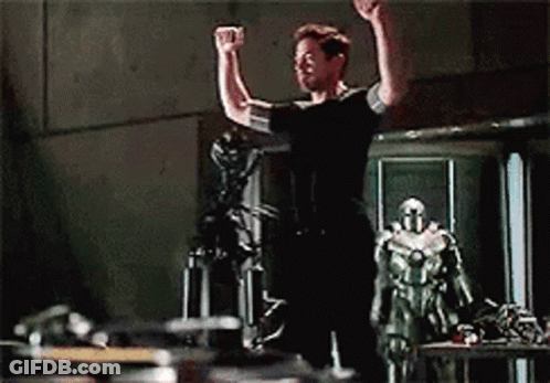 Man In Red Iron Man Suit Standing In Front Of Building GIF