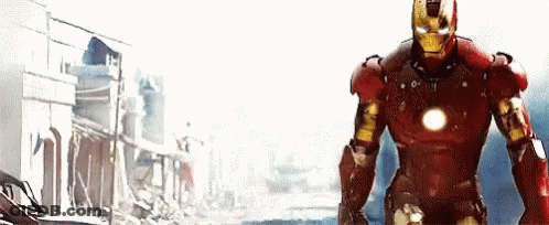 Man In Red Iron Man Suit Standing In Front Of Building GIF