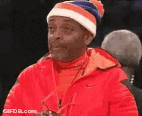 Man In Red Jacket And Blue-White Hat Looking GIF