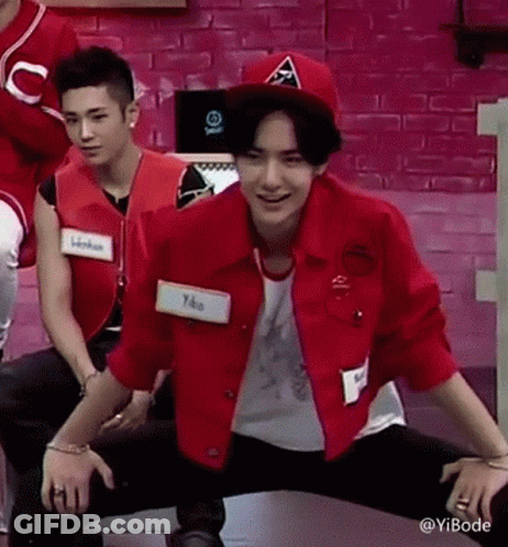 Man In Red Jacket And Hat Kneeling By Pink Wall GIF
