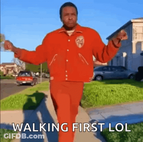 Man In Red Jacket And Red Pants Walking Down Sidewalk GIF