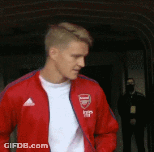 Man In Red Jacket And White Shirt Walking Down Hallway GIF