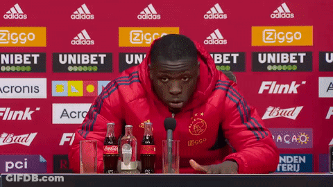 Man In Red Jacket At Table With Coca Cola And Microphone GIF