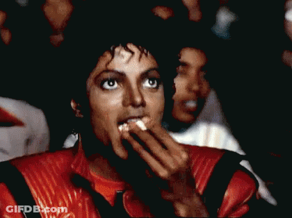 Man In Red Jacket Eating Popcorn In Crowd GIF