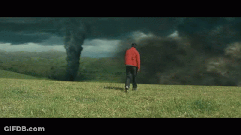 Man In Red Jacket Facing Tornado In Field GIF