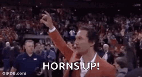 Man In Red Jacket Giving Horns Up In Front Of Crowd GIF