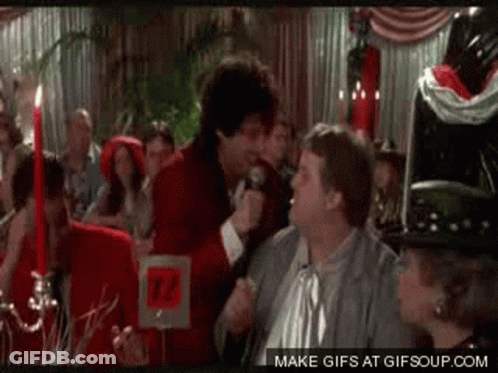 Man In Red Jacket Holding Microphone Talking To Another Man GIF