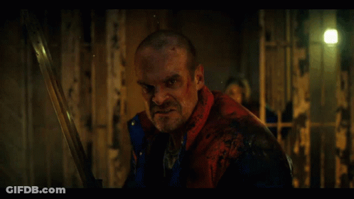 Man In Red Jacket Holding Sword In Dark Room GIF