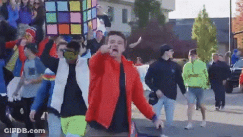 Man In Red Jacket In Front Of Crowd GIF