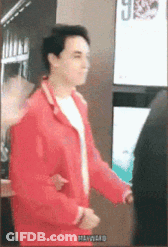 Man In Red Jacket In Front Of Hawaii Sign GIF