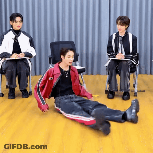 Man In Red Jacket Laying On Floor Two Men Behind GIF
