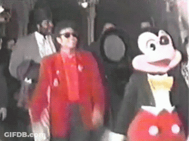 Man In Red Jacket Next To Mickey Mouse Costume GIF