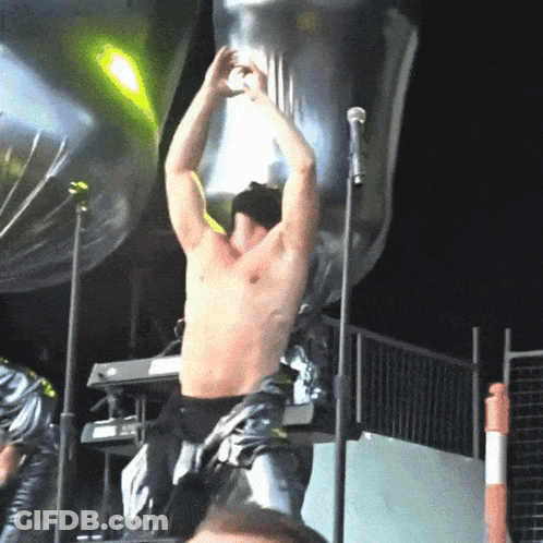 Man In Red Jacket On Stage With Bag On Head GIF