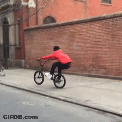 Man In Red Jacket Riding Bike Down Street GIF