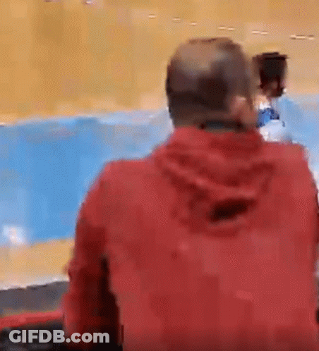 Man In Red Jacket Sitting Against Blue Wall GIF