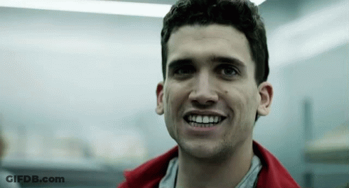 Man In Red Jacket Smiling In Dark Room GIF