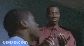 Man In Red Jacket Standing By Woman In Blue Shirt At Desk GIF