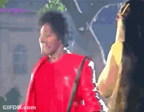 Man In Red Jacket Standing Next To Woman With Long Hair GIF