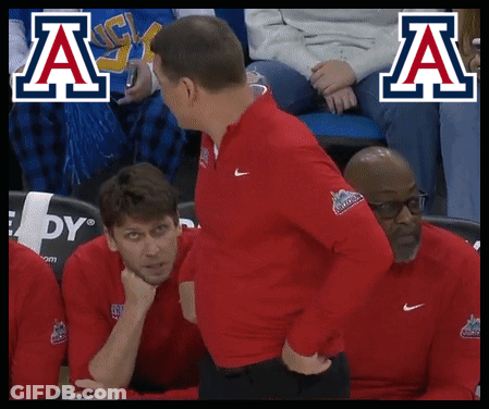 Man In Red Jacket Talking To Man In Blue And White Logo GIF