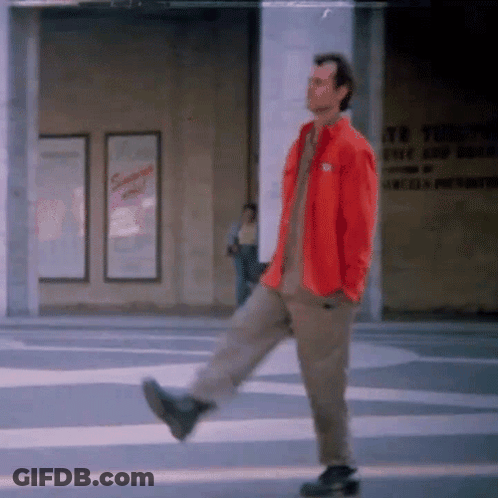 Man In Red Jacket Walking Down Street GIF