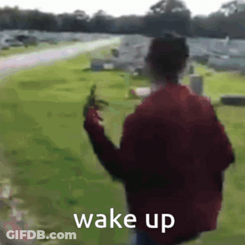 Man In Red Jacket Walking Through Cemetery With Gun Saying Wake Up GIF