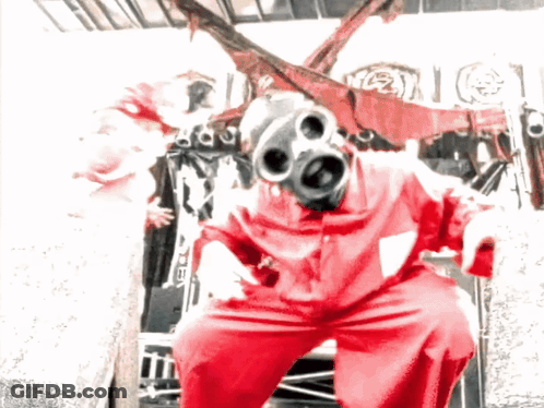 Man In Red Jumpsuit Holding Two Guns GIF