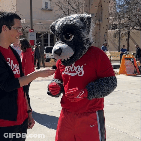 Man In Red Lobos Shirt Talks To Mascot GIF