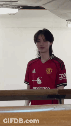 Man In Red Manchester United Jersey Standing By Table GIF
