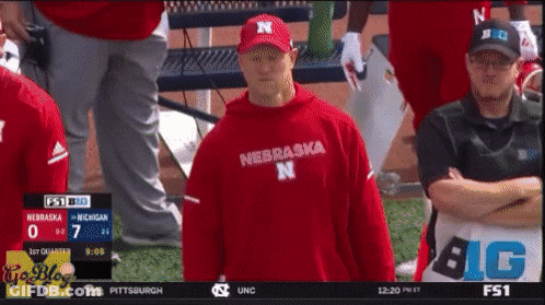 Man In Red Nebraska Shirt In Front Of Scoreboard GIF