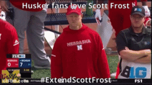 Man In Red Nebraska Sweatshirt In Front Of Scoreboard GIF