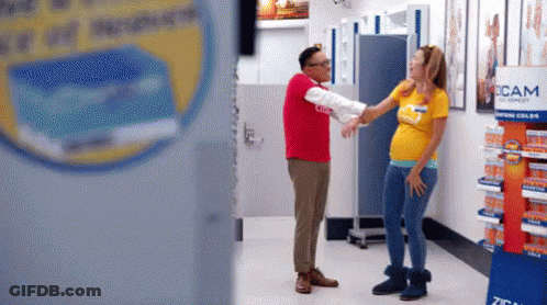 Man In Red Next To Pregnant Woman In Yellow GIF