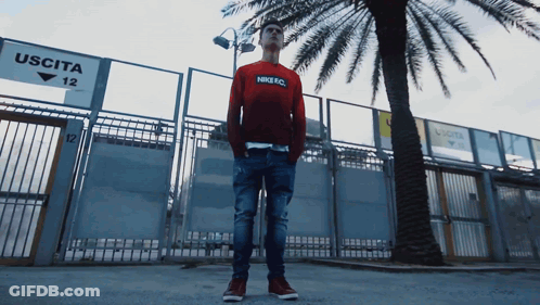 Man In Red Nike FC Sweatshirt In Front Of Uscita 12 Sign GIF