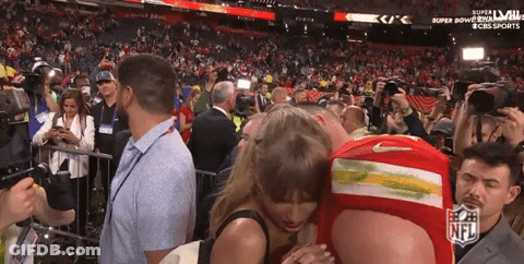 Man In Red Nike Shirt Hugging Woman At Super Bowl GIF