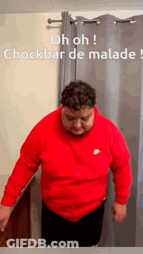 Man In Red Nike Sweatshirt Standing In Front Of Grey Curtain GIF