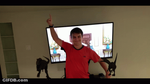Man In Red North Face Shirt Standing In Front Of TV GIF