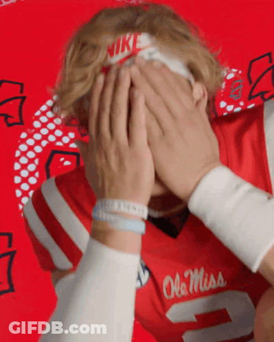 Man In Red Ole Miss Jersey Covering Face GIF