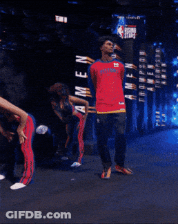 Man In Red Pistons Jersey In Front Of Rising Stars Sign GIF