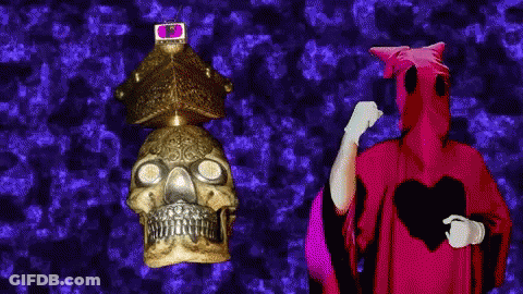 Man In Red Robe Next To Skull GIF