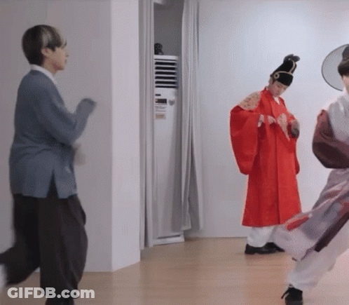 Man In Red Robe Standing Next To Woman In Blue Sweater GIF