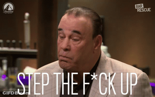 Man In Red Shirt And Black Vest Standing In Dark Room GIF
