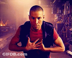 Man In Red Shirt And Black Vest Standing In Dark Room GIF