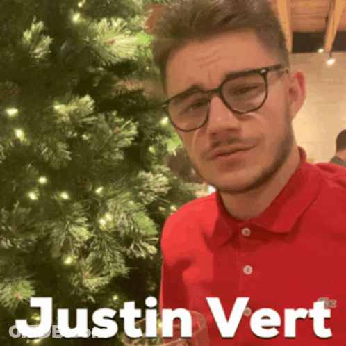 Man In Red Shirt And Glasses In Front Of Christmas Tree GIF